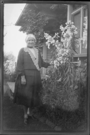 Lydia Williams standing next to lillies in garden area, outside of house, unknown location