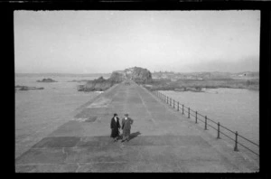 Unidentified man and woman on sea wall heading to town, Brittany, France