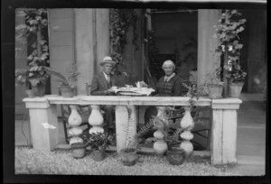 William and Lydia Williams seated at an outside table having tea, including pots plants in foreground, Venice, Italy