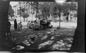 Group of unidentified women, children and baby carriages in a park, including buildings and trees, Naples, Italy