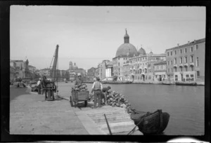 Unidentified men loading wine bottles on wharves beside the Grand Canal, Venice, Italy