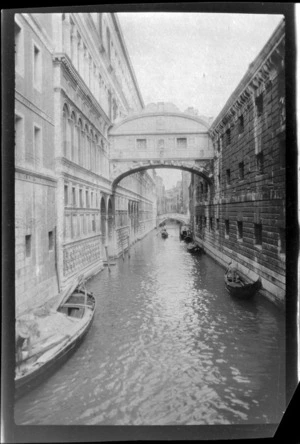 Looking down canal with covered stone bridges between buildings, Venice, Italy