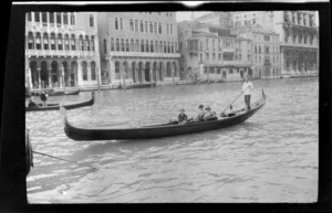 Gondolier with three passengers on the Grand Canal, including palazzo style buildings in the background, Venice, Italy
