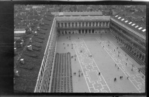 View of St Mark's Square from above, showing rooftops, tables, chairs and people in the square, Venice, Italy