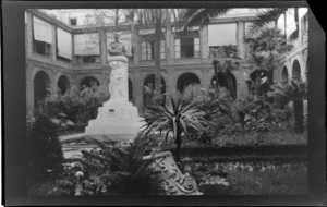 Fountain statue with a sculptured figure and a bust of Vittorio Emanuele III on top, with plaque underneath, in a courtyard garden, Rome, Italy