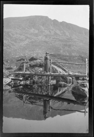 Lydia Williams standing on wooden bridge over stream, with mountain in background, Killarney, County Kerry, Ireland