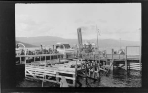 Passengers on board a paddle-wheel steamer next to jetty, unknown location, Scotland
