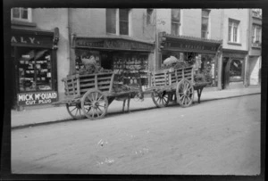 Street scene, donkeys and carts filled with peat outside shops, (Mick McQuaid, Mangan jeweller, E Meacher, and Hussey confectionary), Killarney, County Kerry, Ireland