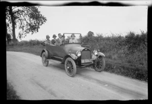 Lydia Williams sitting in middle of back seat of vehicle, including four other people in vehicle, driving along country road, unknown location, England