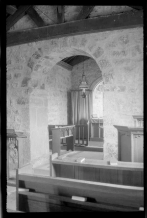 Interior view of unidentified church, showing stone wall and wood furniture, probably Corbridge, England