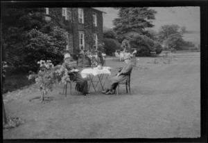 Three groups having tea on lawn outside large house, including Lydia Williams on front table, with unidentified woman, Lake District, England, United Kingdom