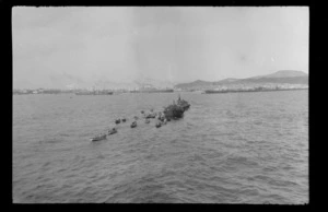 Cluster of small boats surrounding two steam ships in harbour, location unidentified