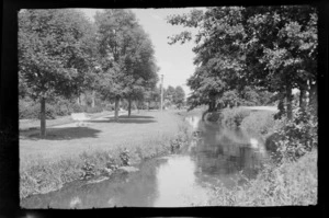 Stream running through a park, bordered by trees and benches, location unidentified