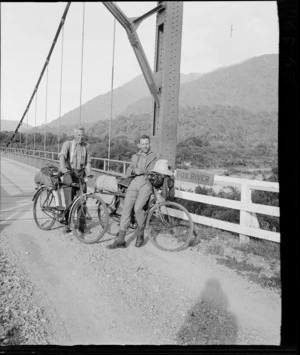 Edgar Williams and an unidentified man, with bicycles, on a suspension bridge over the Fox River, Buller District, West Coast Region