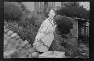Wooden ornament, woman figurehead from bow of ship, next to sundial, in garden area of home