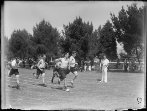 Boys' running race at Westport Technical High School, West Coast Region, showing runners crossing the finish line, officials, and spectators shaded by trees in background