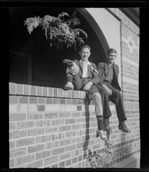 Two unidentified schoolboys sitting in an arched opening in brick wall, at Westport Technical High School, West Coast Region