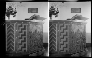 Pulpit at Kawhia Methodist Memorial Church, decorated with Maori carvings and tukutuku panels, brass plaque on wall behind, Waikato Region