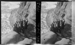 Group of unidentified schoolgirls from Westport Technical High School, standing on limestone cliff, view of surf below, Cape Foulwind, Buller District, West Coast Region