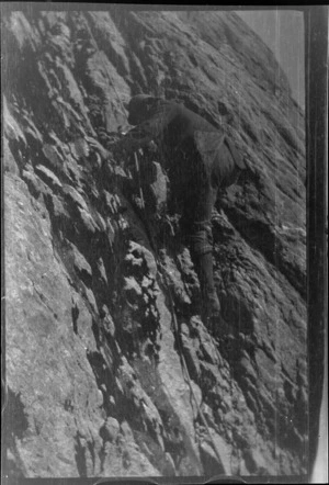 An unidentified mountain climber scaling a cliff with rope, [Fiordland National Park?]