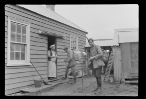 Edgar Williams, right, and climbing companion [Tracy Thomas Gough?], talking to an unidentified man [a cook?] outside a wooden building, Ashburton District, Canterbury Region