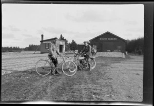 Edgar Williams, with bicycle, and an unidentified man [Tracy Thomas Gough?] with motorcycle, at Mount Somers railway station, Ashburton District, Canterbury Region