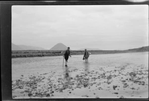 Edgar Williams, on left, and another man [Tracy Thomas Gough?], standing a in a river [Rakaia River?], mountains beyond, Canterbury Region