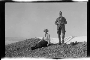 An unidentified man and woman on a shingle slope in the snow, showing the man smoking a pipe, Mount Torlesse, Canterbury Region