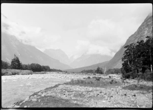 View of river valley [Hollyford Valley?], surrounded by mountains obscured by clouds, [including Mount Tutoko, Darran Range?], Southland District