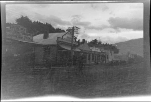 A street with business premises including Pyne & Company, a tailors and outfitters, and a public bar, possibly West End, Kaikōura