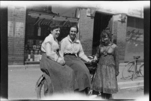 Three unidentified women with a bicycle, outside the business premises of Andrew Lees Ltd, supplier of paperhangings, paint and glass