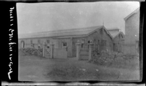 Buildings with stone wall and wooden gate, location unidentified