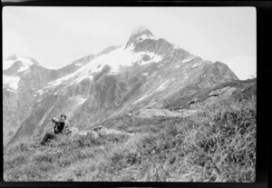 William Grave and an unidentified woman sitting on mountain slope, [Mackinnon Pass?], Milford Track, Southland District