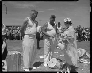 Her Majesty Elizabeth, the Queen Mother, examining a woodchopping competitor's axe at a civic welcome in Napier