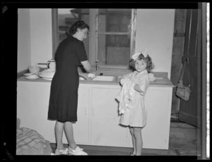 A woman and small girl washing dishes in cottage kitchen, at Polish children's refugee camp, Pahiatua