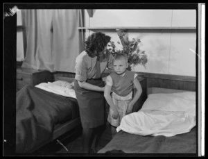 An unidentified woman helping a young boy to get dressed, at Polish children's refugee camp, Pahiatua