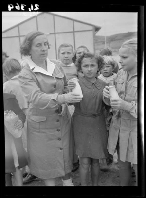 Teacher Miss Rolinska passes a bottle of milk to Stefania Serdynska at a Polish refugee camp, Pahiatua