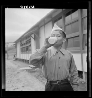 A young boy drinks a bottle of milk at a Polish refugee camp, Pahiatua
