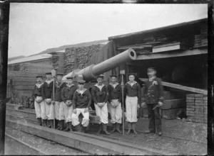 Representation of a cannon beside a group of men dressed as sailors with their officer, ready for procession in Petone to celebrate the end of the South African War