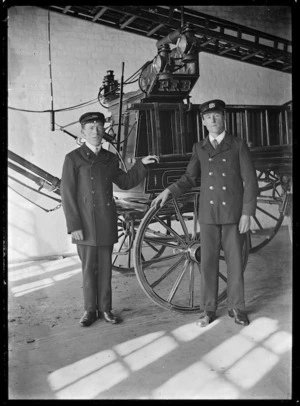 Two firemen standing beside the engine at the Petone Fire Station.