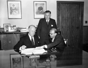 Prime Minister, Sidney Holland and Minister of Social Security, Eric Halstead, with Australian representative, sign Social Security Agreement with Australia, December 1955.