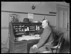 Man, possibly Mr Monro, at a roll top desk, probably Christchurch region
