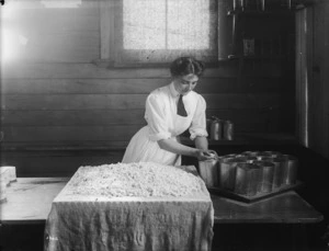 Young woman filling moulds with milk curd in a dairy