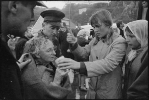 Elderly female survivor from the Wahine shipwreck being served soup on Seatoun beach, helpers include Salvation Army Captain David Bennett