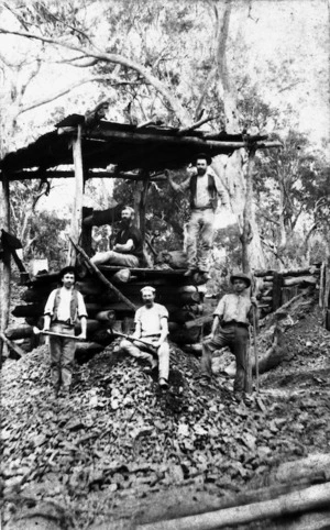 Gold miners standing beside mine shaft