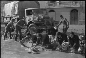 New Zealand soldiers cleaning a truck, and local Italian women washing their linen, near Alife, Italy, during World War 2