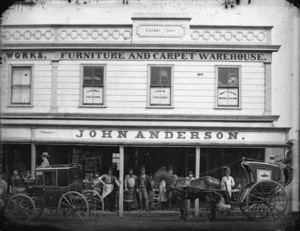 Exterior of John Anderson's furniture and carpet warehouse, in Wanganui, with crowd and carriages alongside