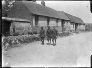 New Zealand soldier and two American soldiers walking past houses in Bertrancourt, France
