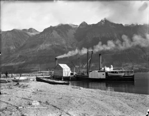 Scene at Lake Wakatipu with paddle steamer and mountain range