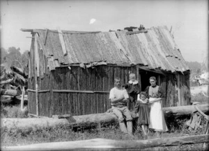 George Edward Reid, Annie Reid, and children, alongside a hut, Taihape
